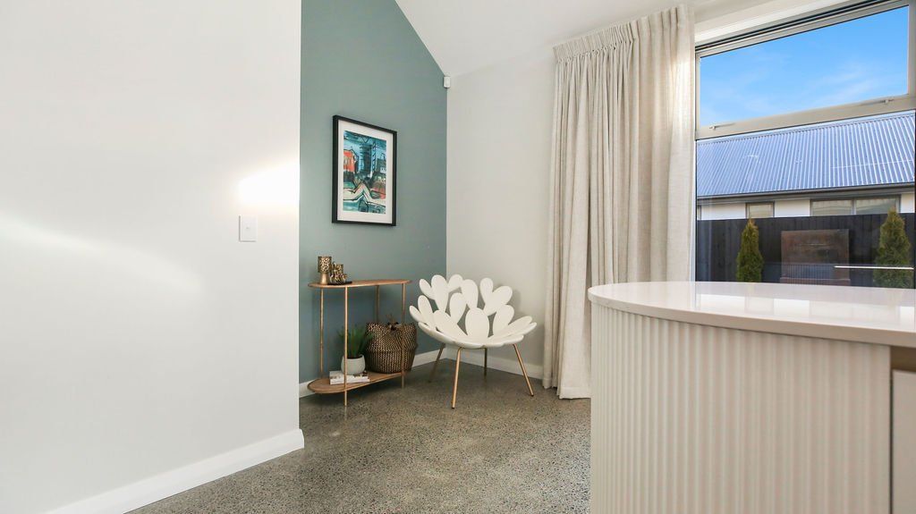 A living room with a chair , table , and window.