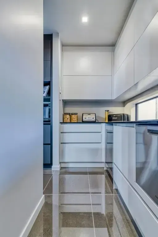 A kitchen with white cabinets and black counter tops