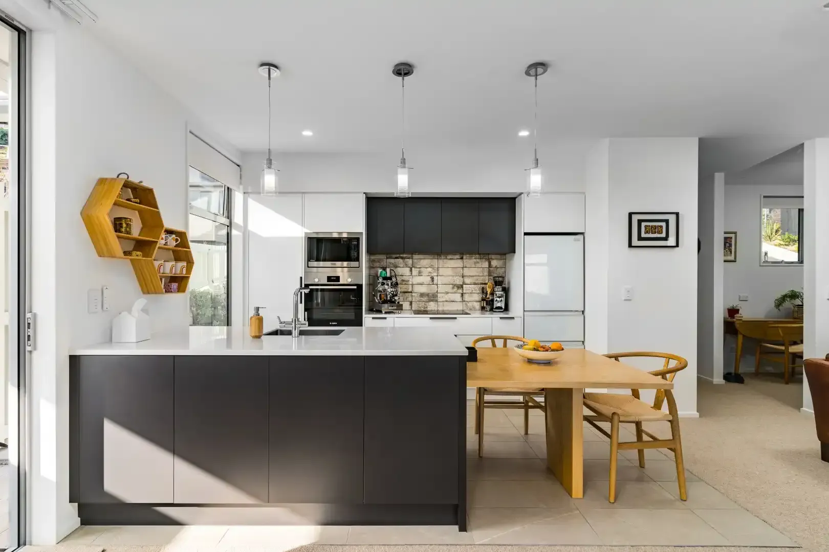 A kitchen with black cabinets and a wooden table and chairs.