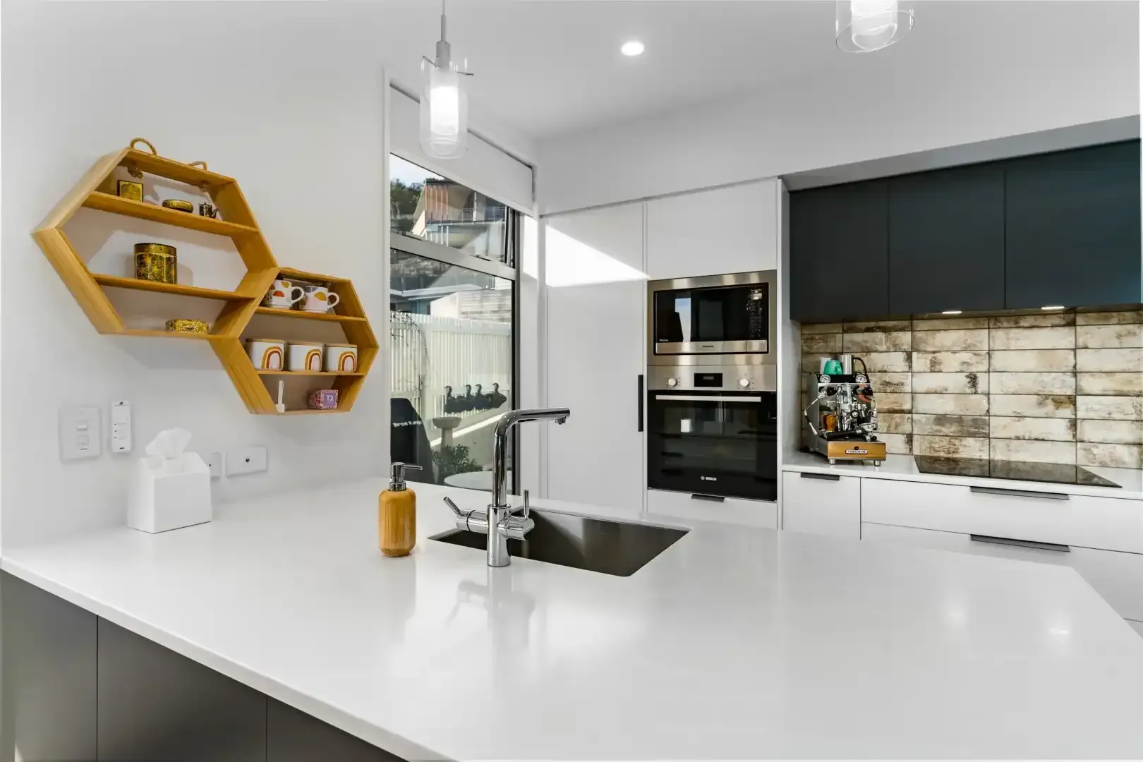 A kitchen with white cabinets , stainless steel appliances , a sink , and a honeycomb shelf.