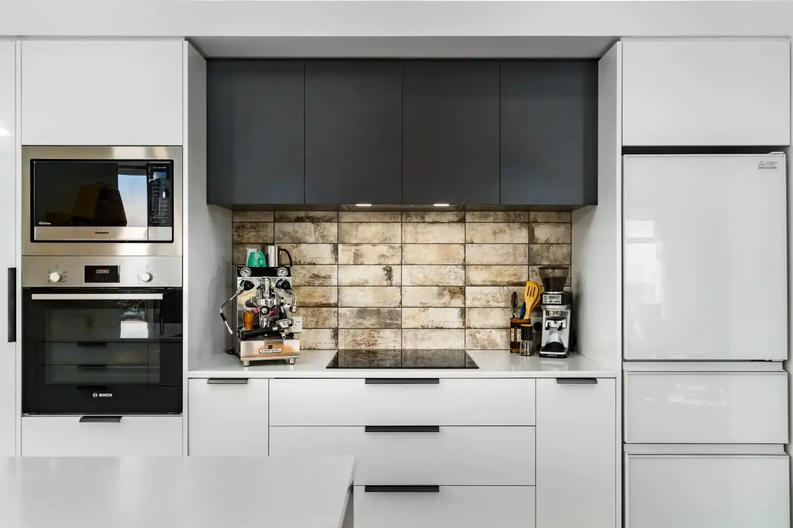 A kitchen with white cabinets , a refrigerator , a microwave , and a stove.
