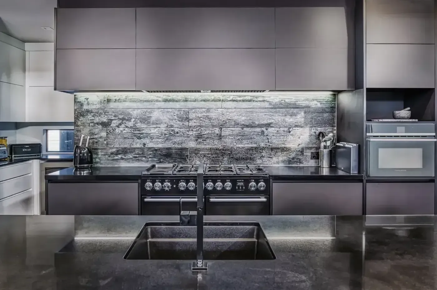 A kitchen with a sink , stove , oven and microwave.