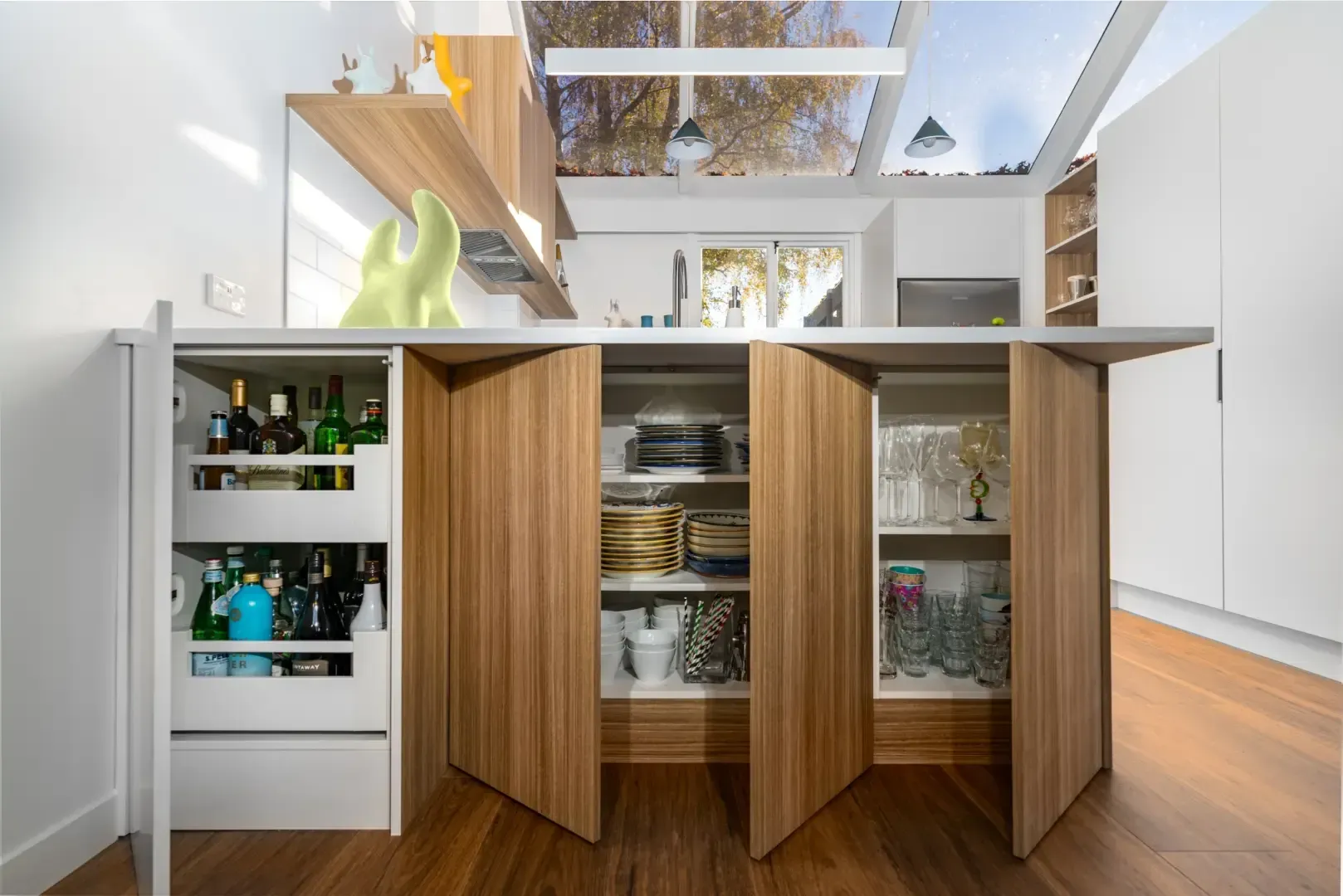 A kitchen with wooden cabinets and shelves and a bar.