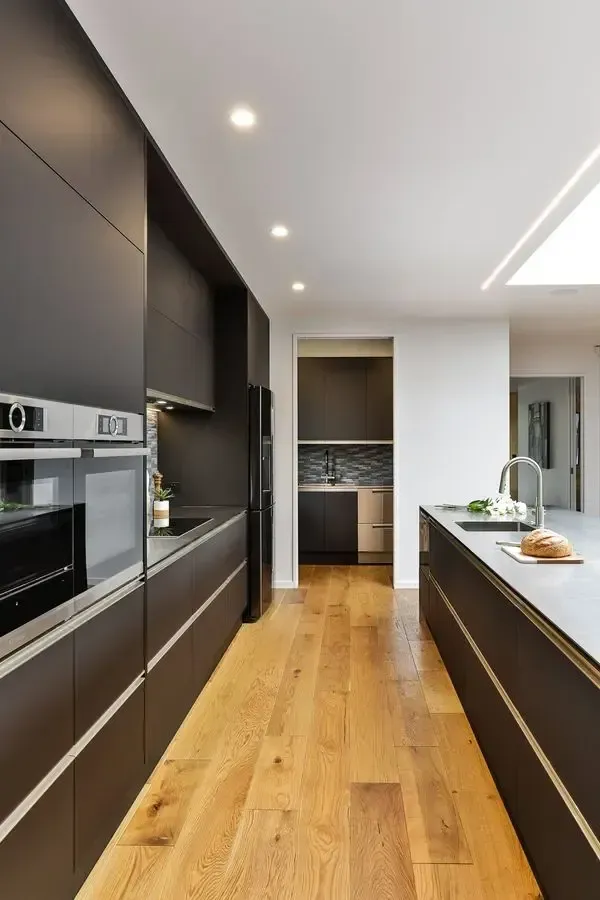 A kitchen with black cabinets and wooden floors