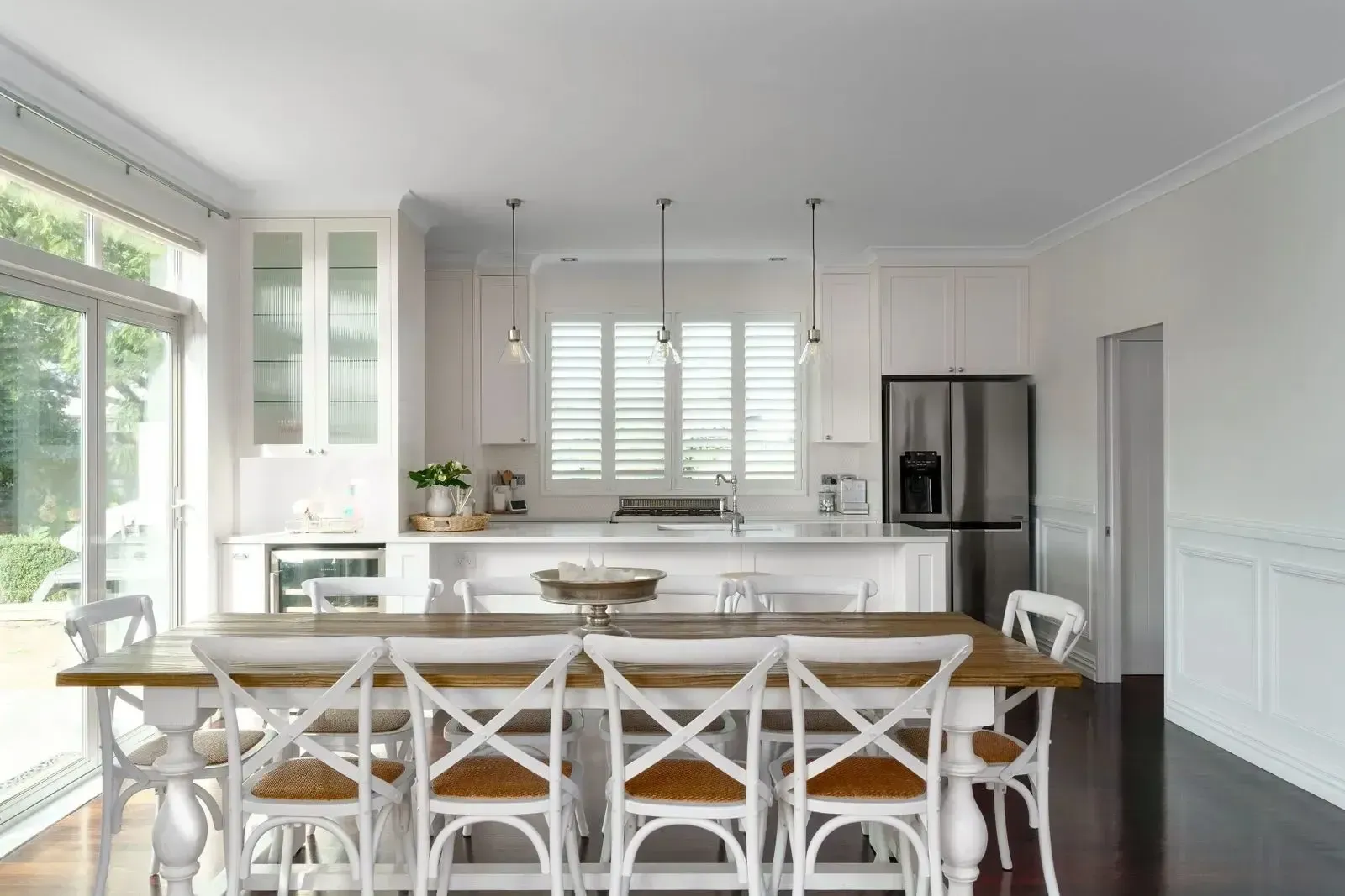 White kitchen and dining area, light wood table with white chairs.