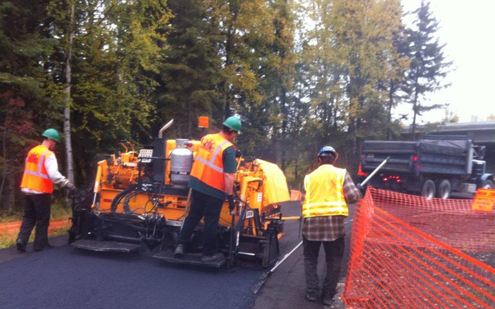 A group of construction workers are working on a road.