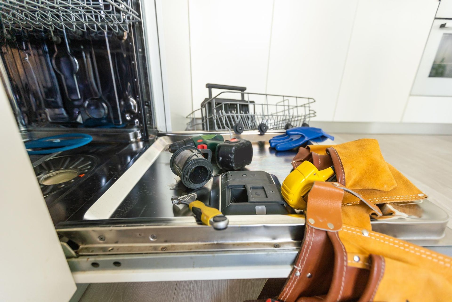 Open suitcase with drone parts, tools, and yellow bag on a table near white cabinets