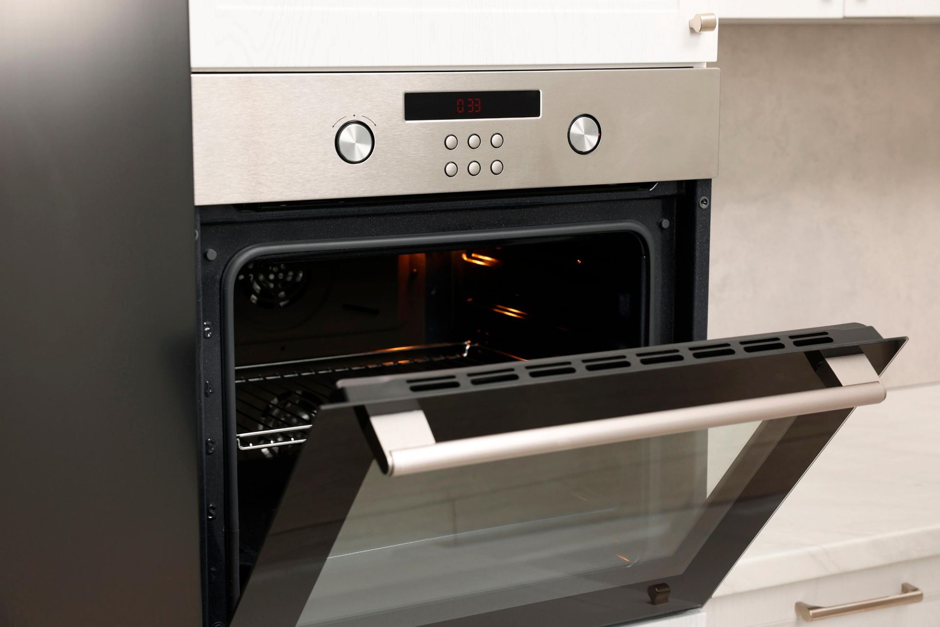 Open oven with glass door and lit interior in a modern kitchen