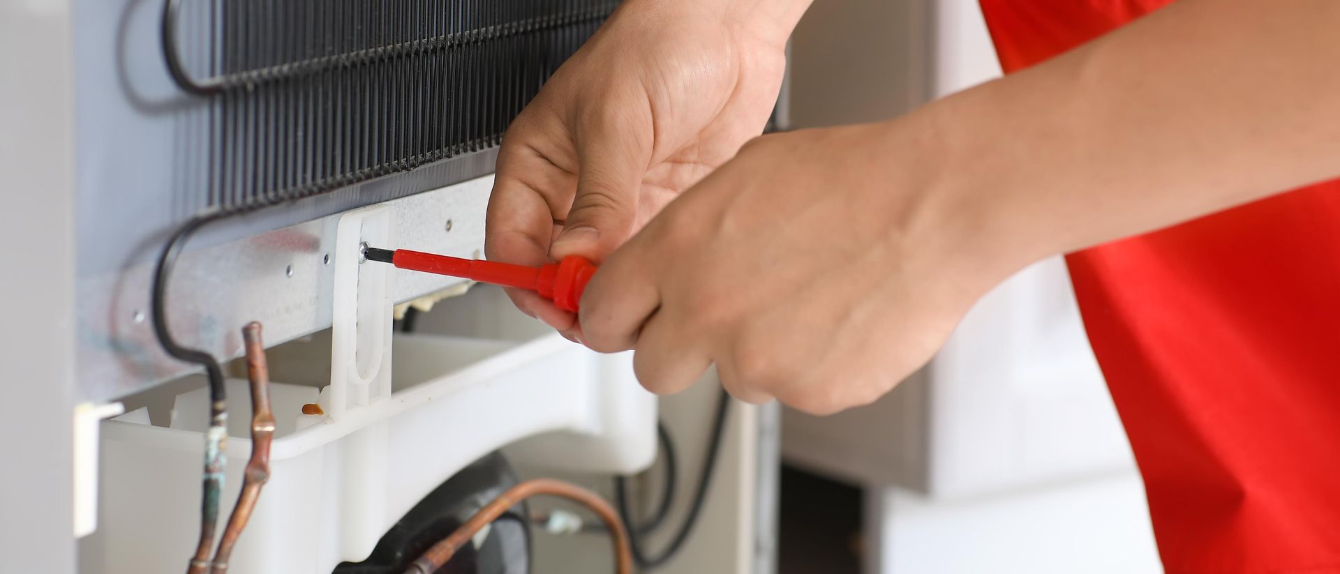 Person using a screwdriver to adjust wiring inside an electrical panel