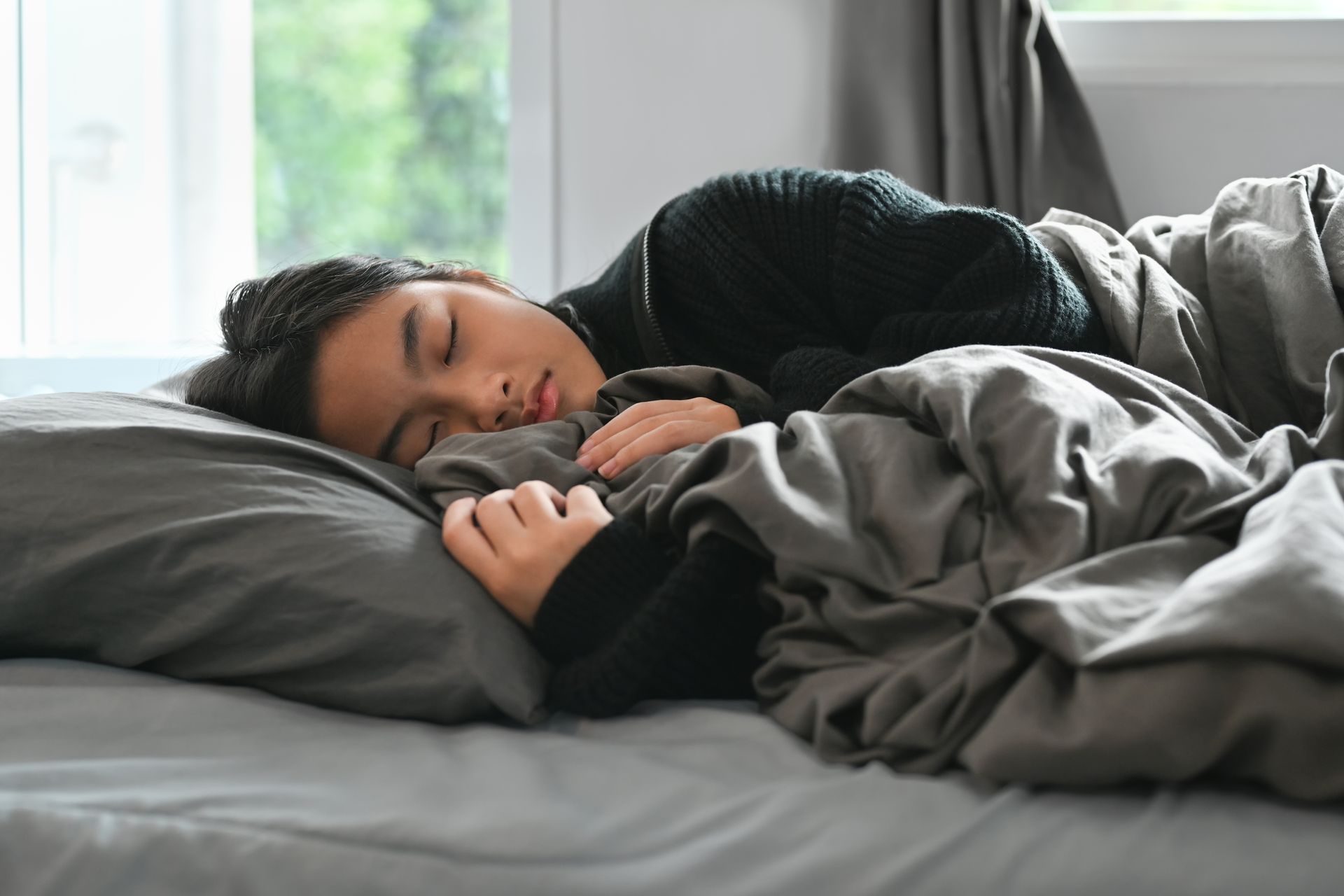 A woman is sleeping on a bed with a blanket and pillow.