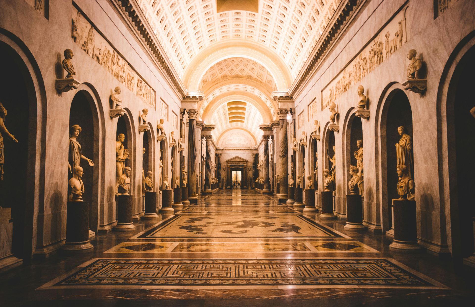 Grand ornate palace hall with arched ceiling, gilded columns, and patterned marble floor in warm light