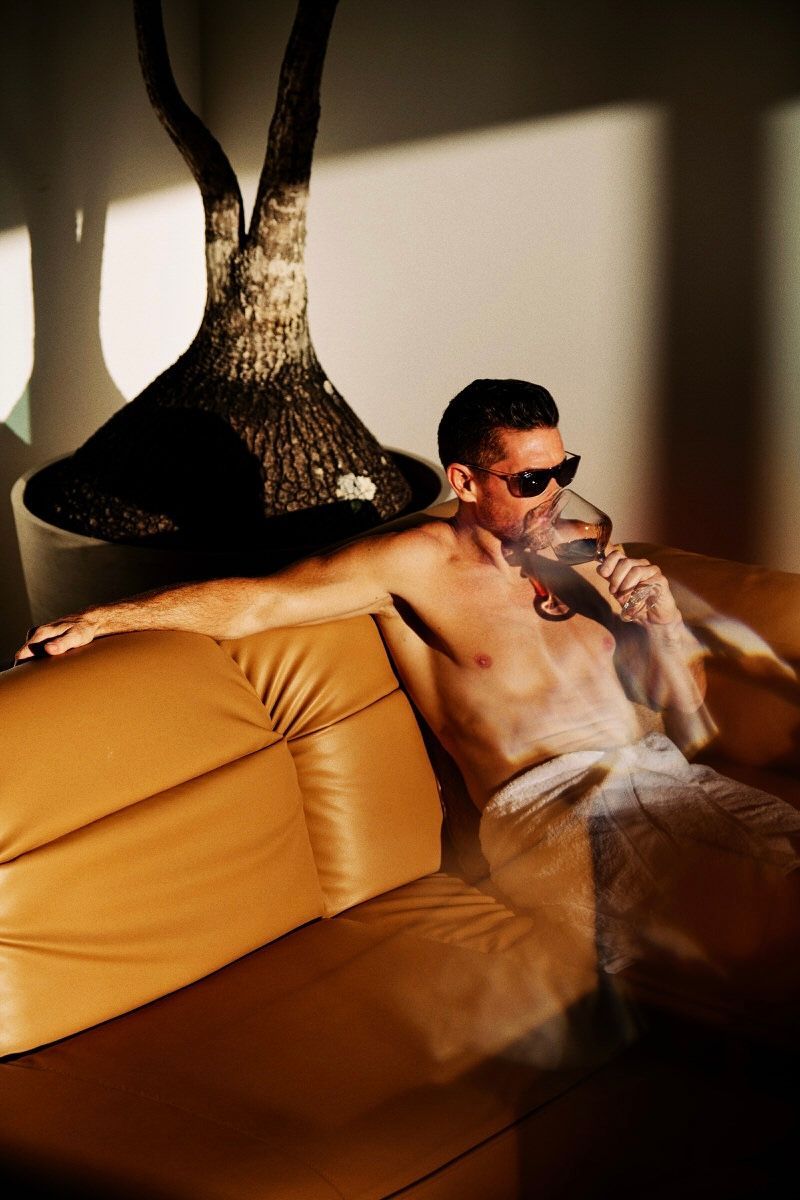 Attractive man enjoying a fine wine, lounging in a golden sunset