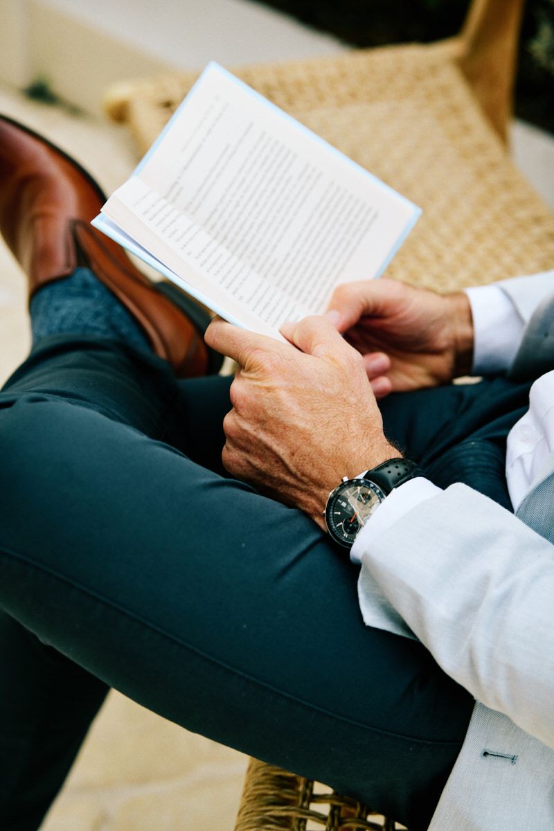 Well-dressed man reading a book in an outdoor setting