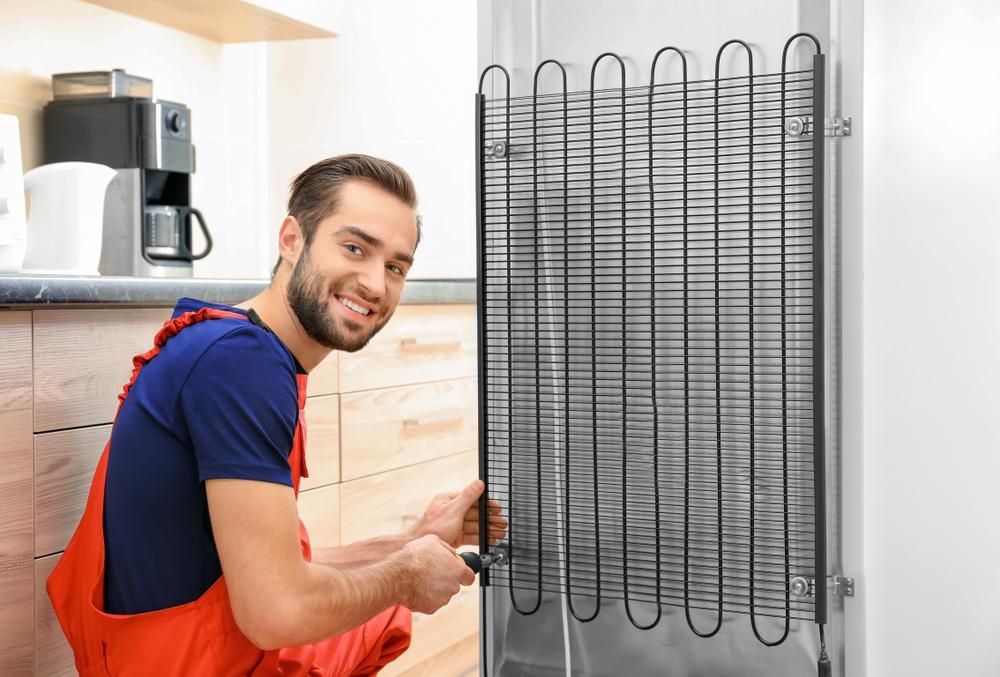A Man Is Fixing A Refrigerator In A Kitchen — Accent Electrics In Noraville, NSW