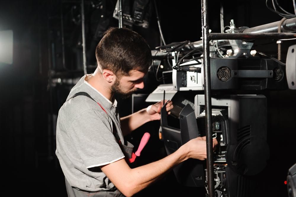 A Man Is Working On A Machine In A Dark Room — Accent Electrics In Noraville, NSW