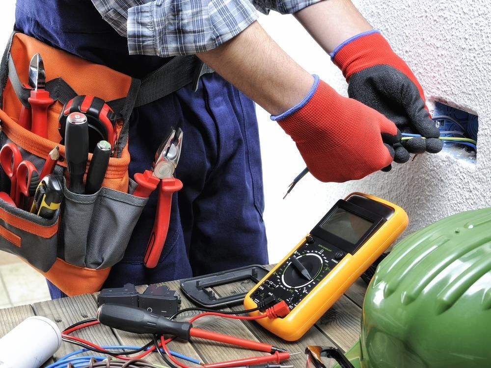 An Electrician Is Working On An Electrical Outlet With A Multimeter — Accent Electrics In Noraville, NSW