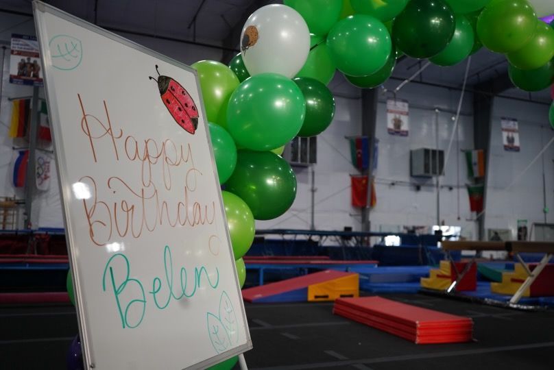 A white board with green balloons and a ladybug on it.