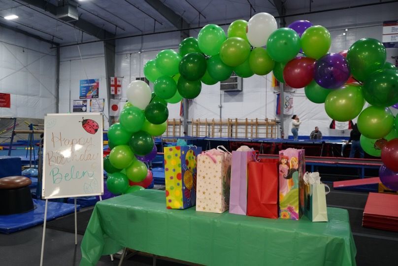 A table with balloons and gifts on it in a gym.
