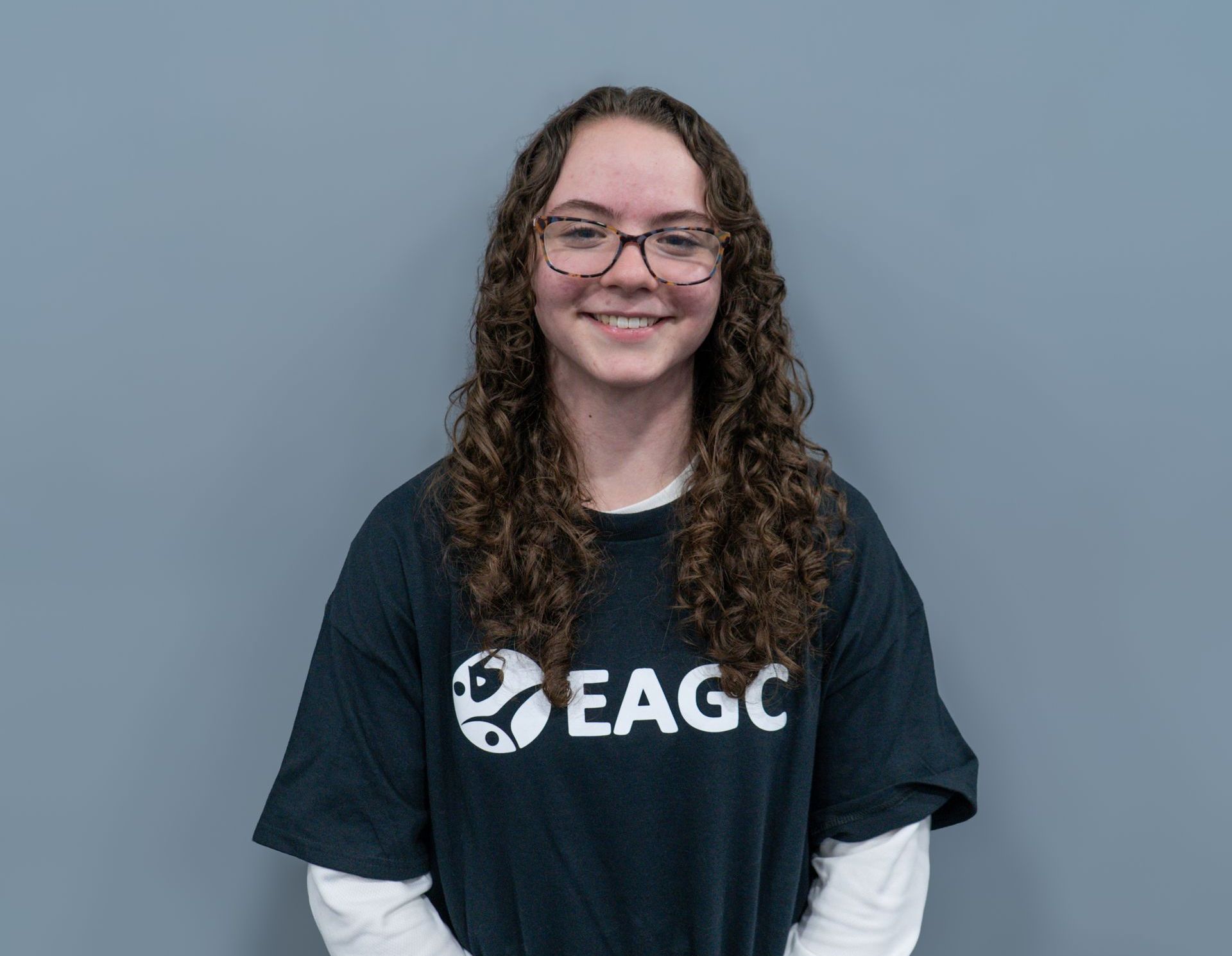 A smiling woman in a black EAGC t-shirt.