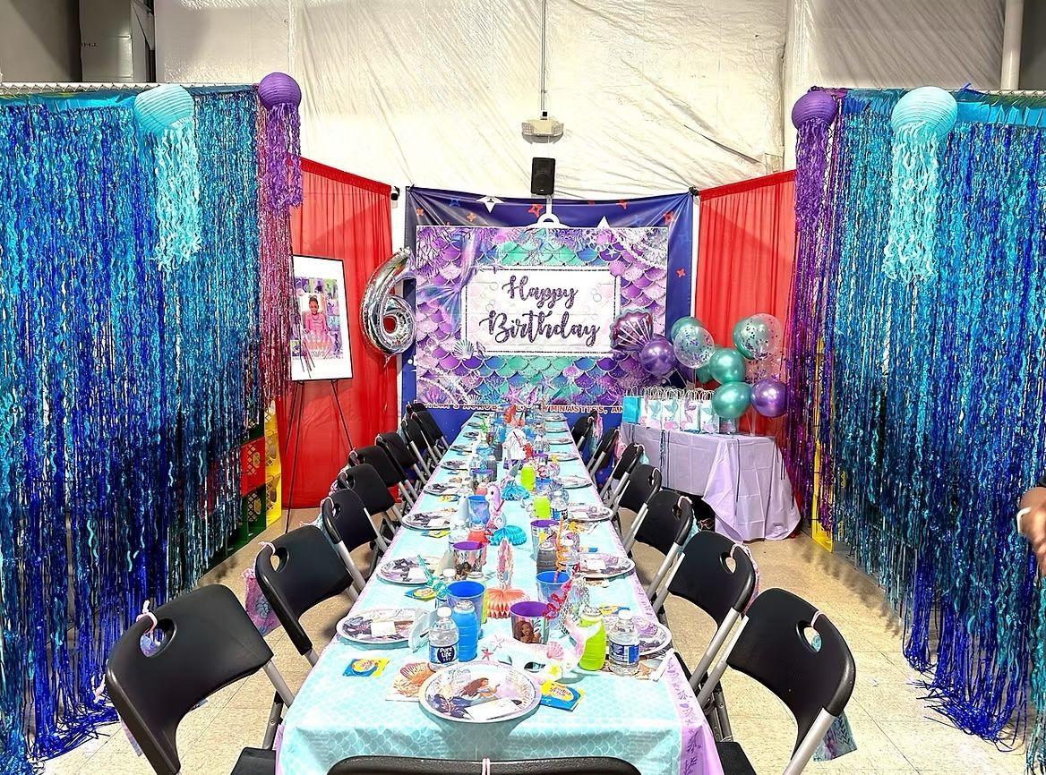 A room decorated for a birthday party with a long table and chairs.