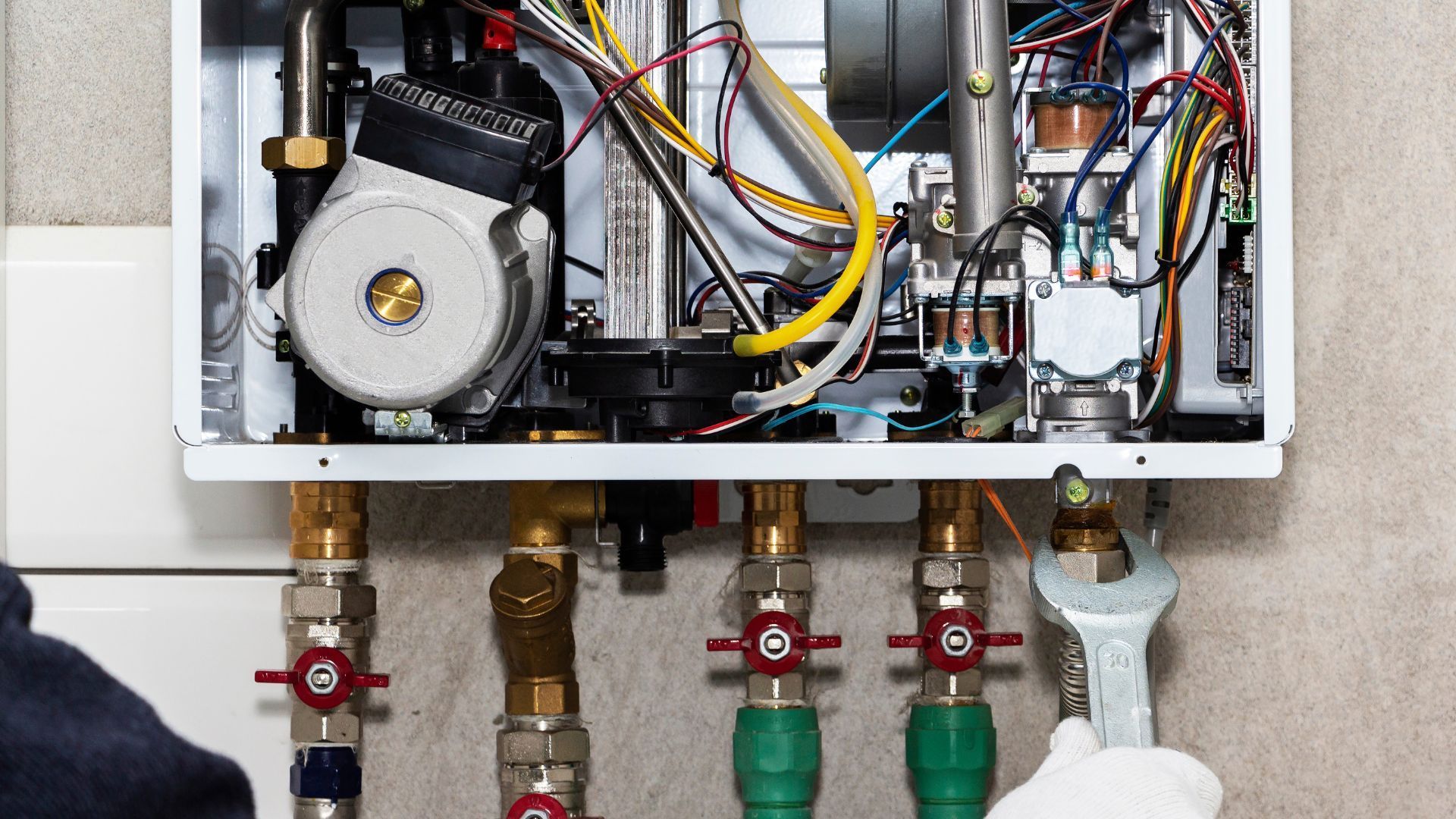 A man is working on a boiler with a wrench.
