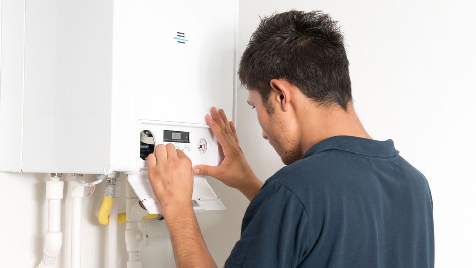 A man is installing a boiler on a wall.