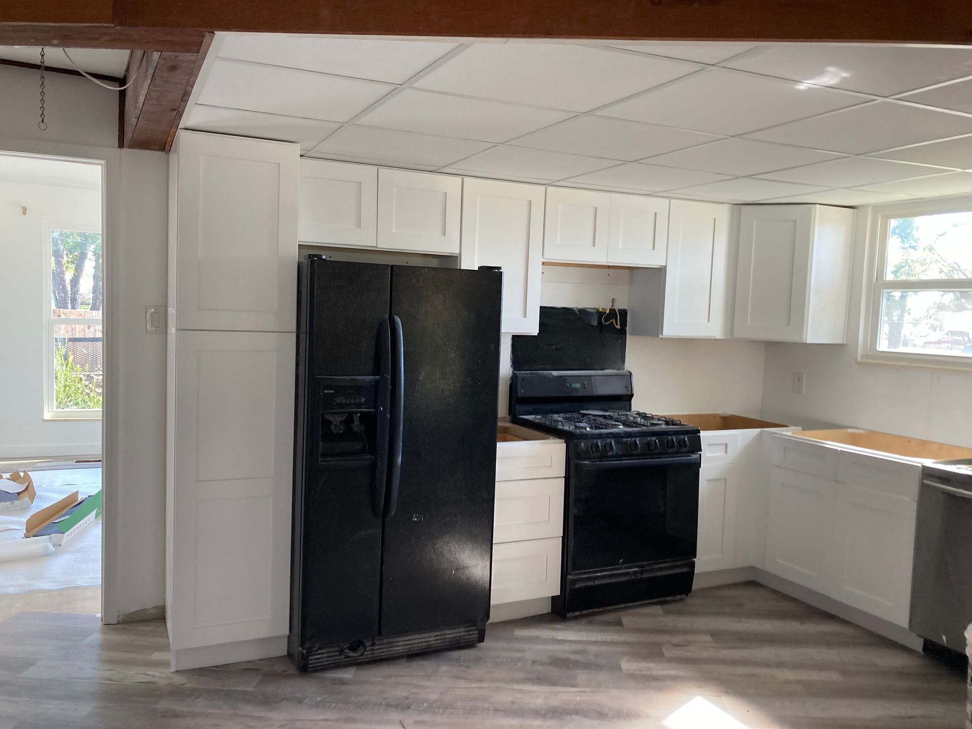 Small kitchen with black refrigerator and stove, white cabinets, and a partially open windowed wall.