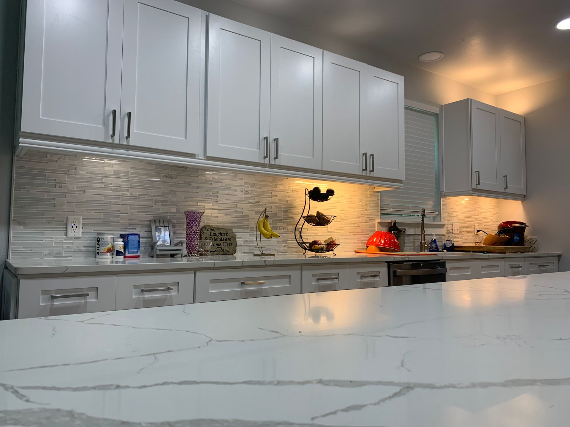 Modern kitchen with white cabinets, stone backsplash, and a marble countertop