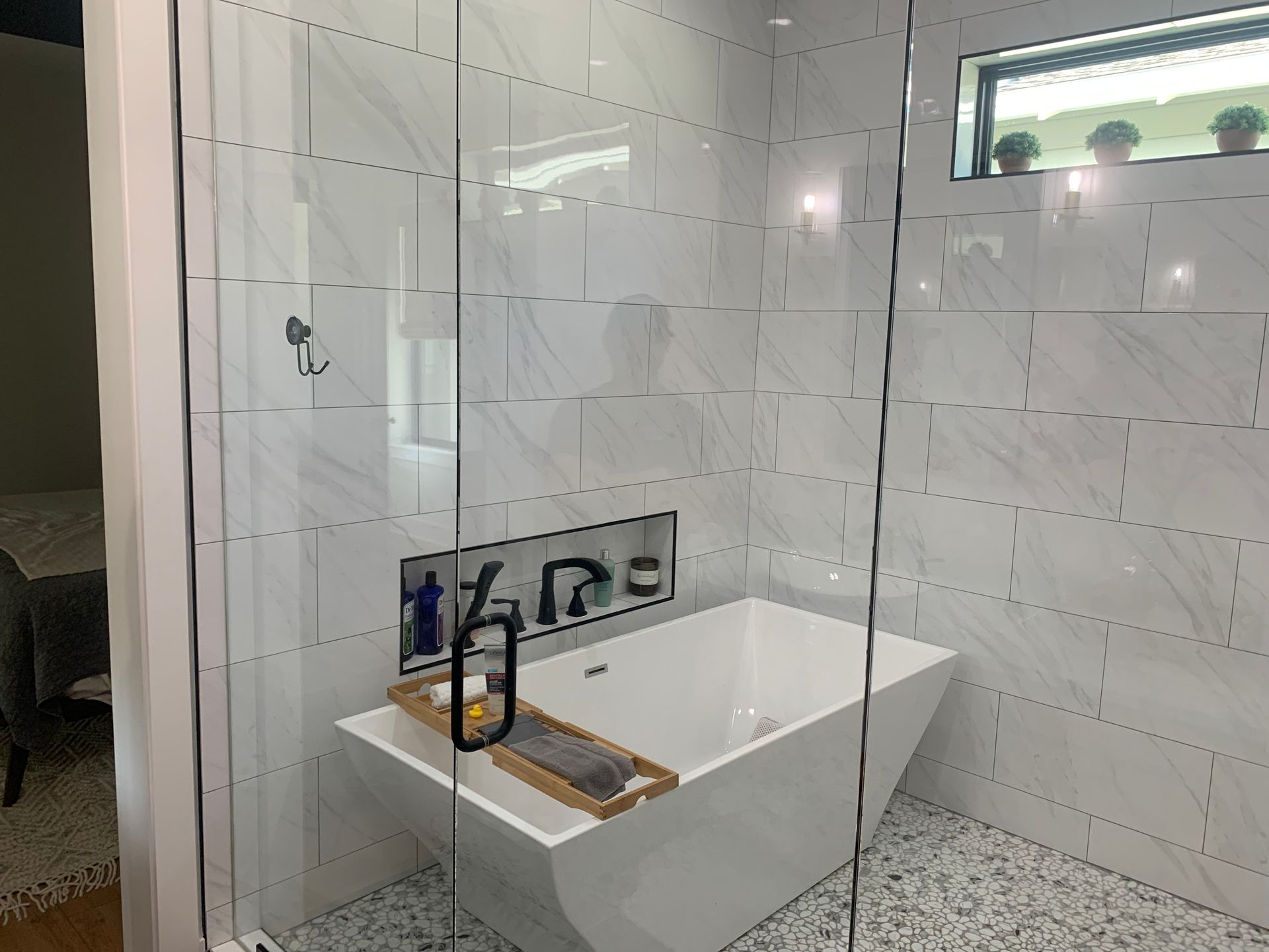 Modern bathroom with a white freestanding tub, black faucet, and glass shower enclosure