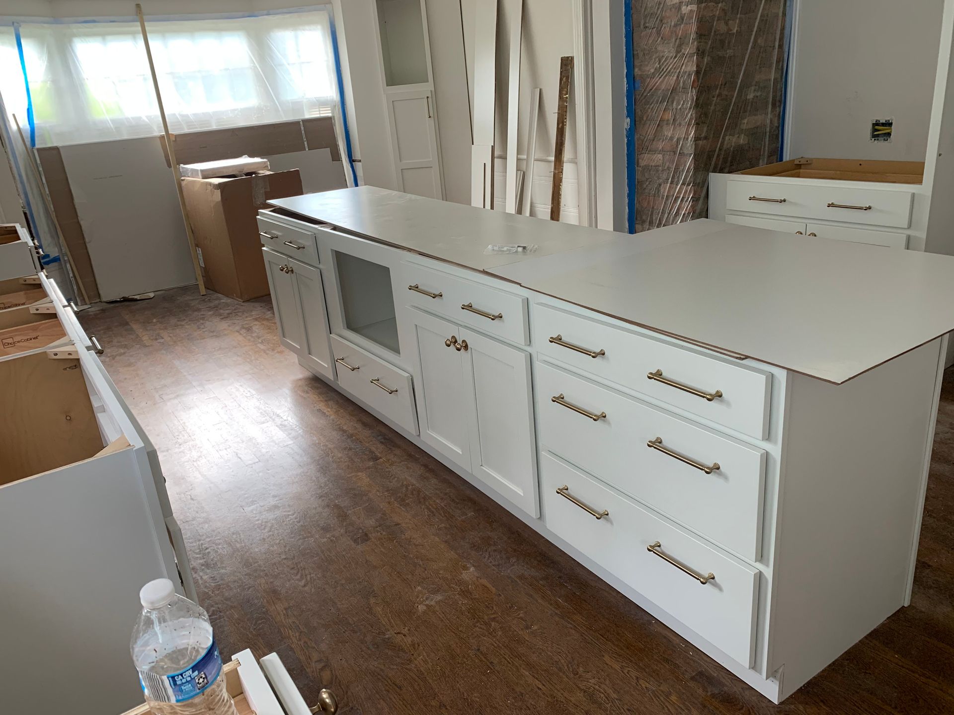 Modern white kitchen island with drawers, countertop, and microwave in a bright unfinished room