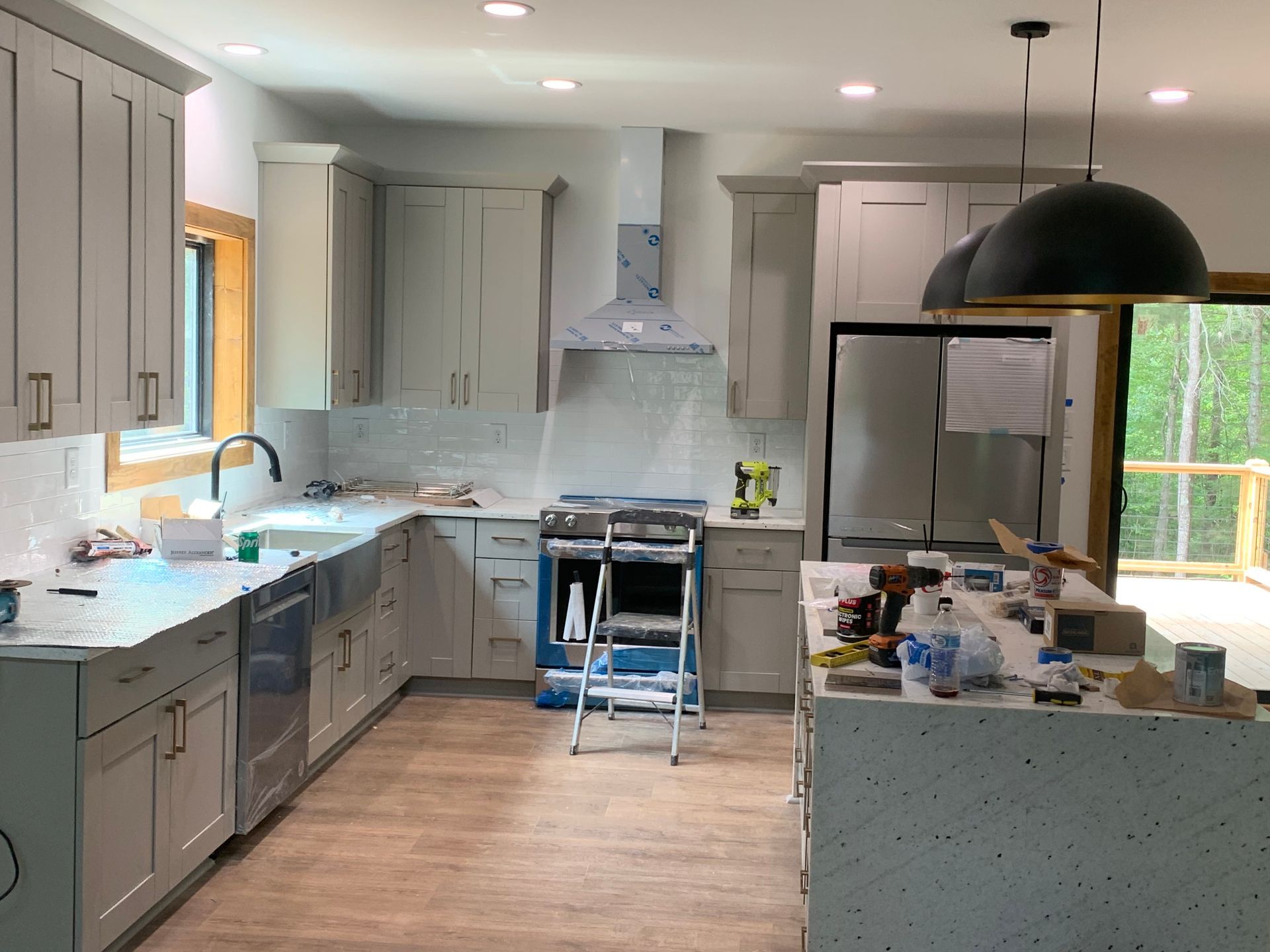 Bright modern kitchen with gray cabinets, wood floors, and a central island under renovation