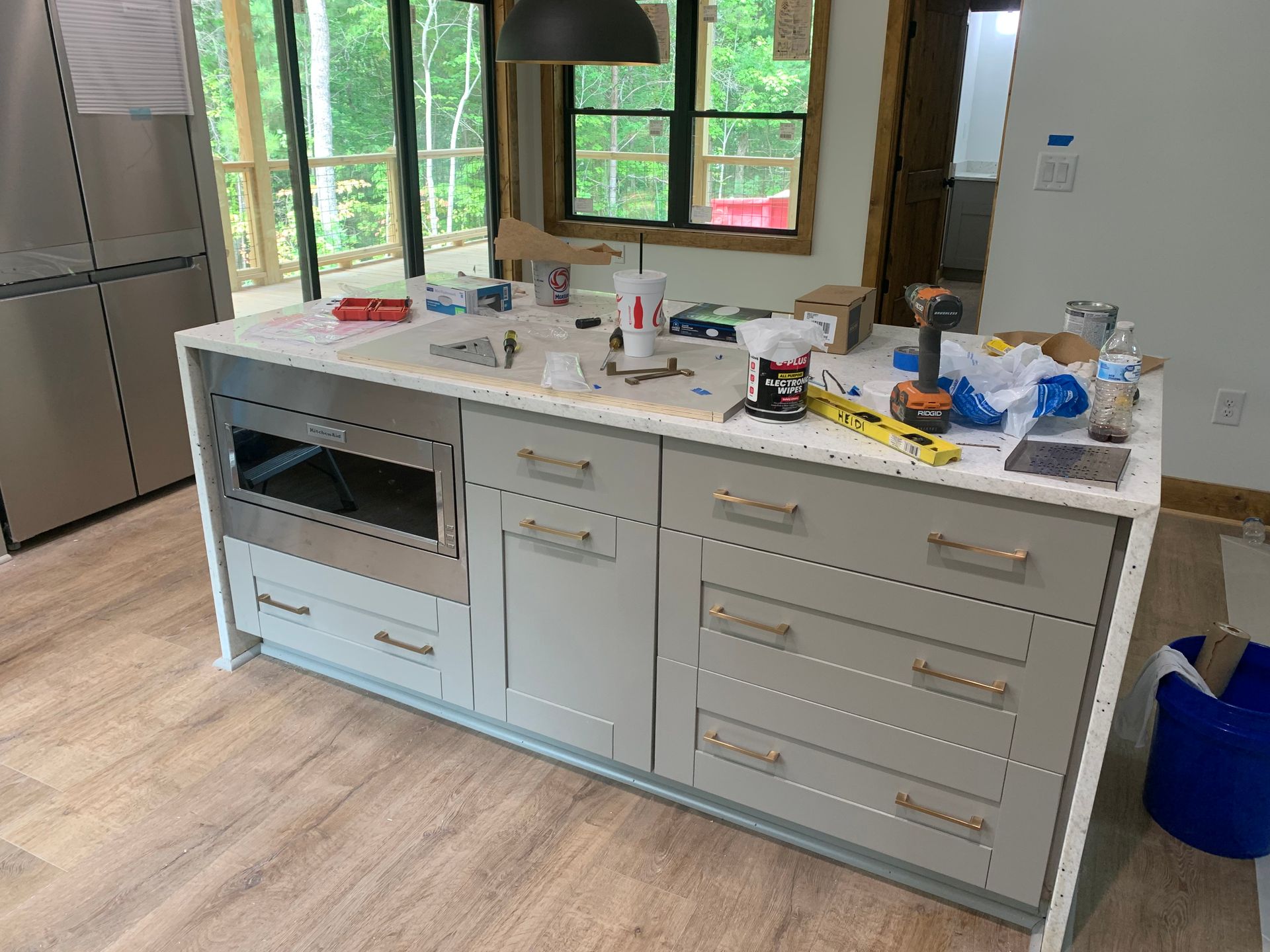 Kitchen island cluttered with dishes, tools, and appliances in a bright modern kitchen