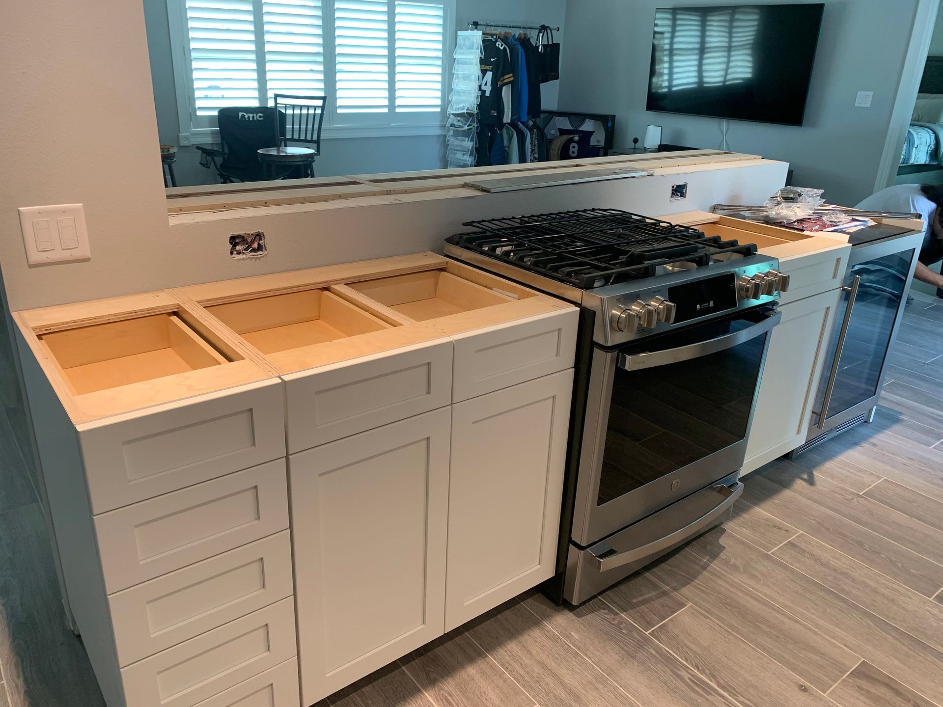 Kitchen remodel with unfinished cabinets, granite countertop, and stainless steel stove beside a mirrored backsplash
