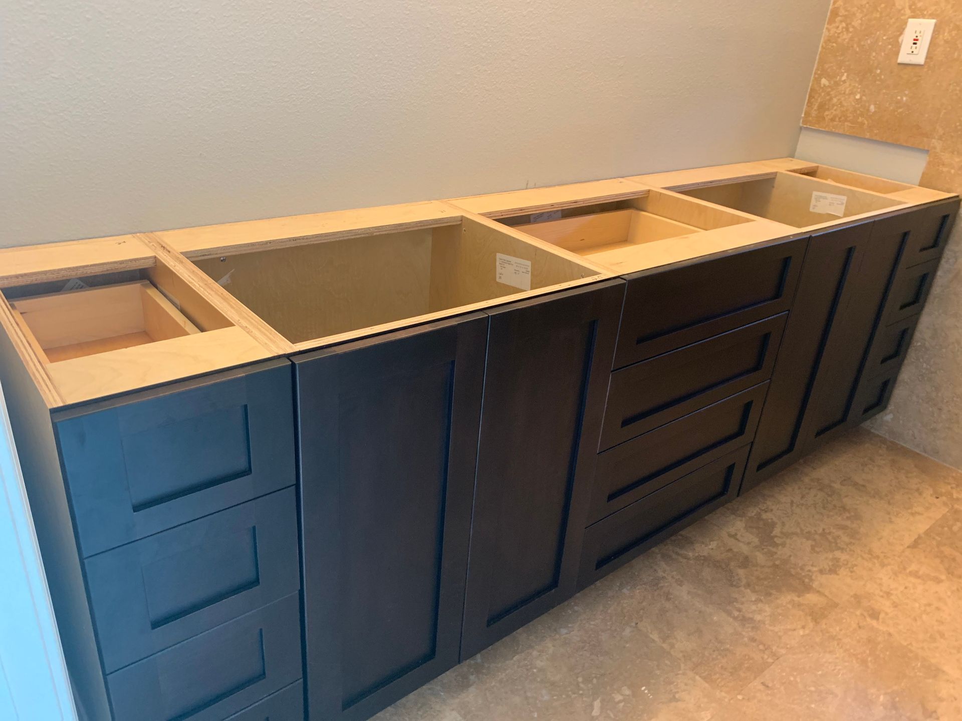 Unfinished dark blue bathroom vanity cabinets with a wood countertop and sink cutouts along a wall