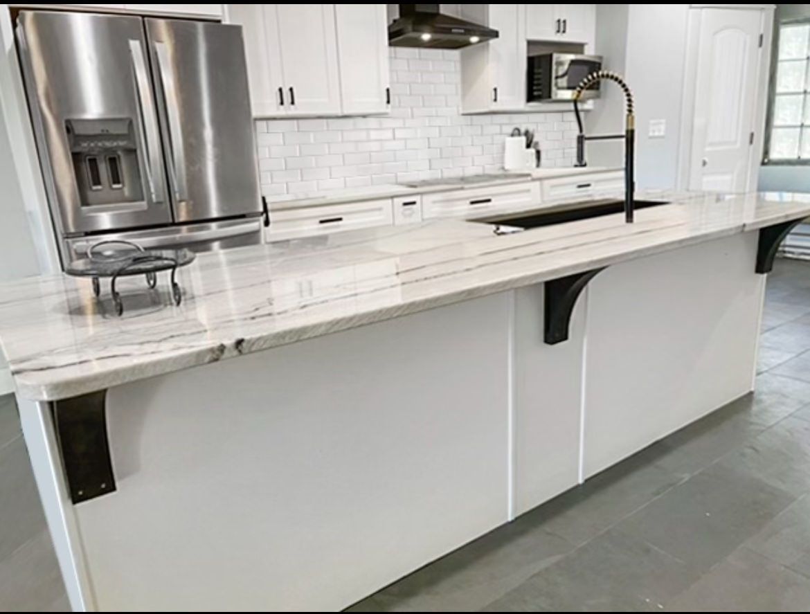 Modern white kitchen with marble island, stainless-steel fridge, and black faucet