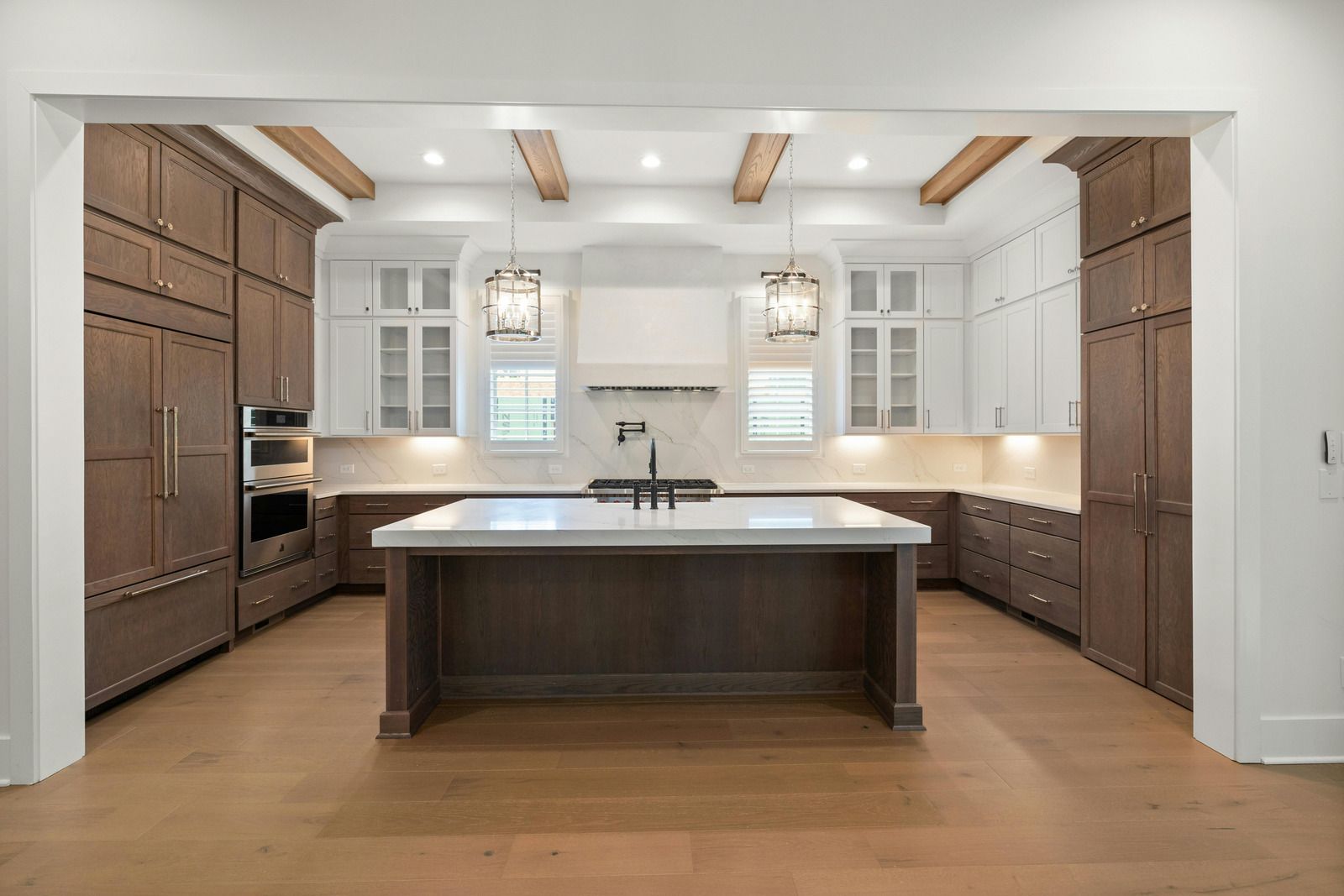Spacious modern kitchen with white cabinets, dark wood island, and light wood floors