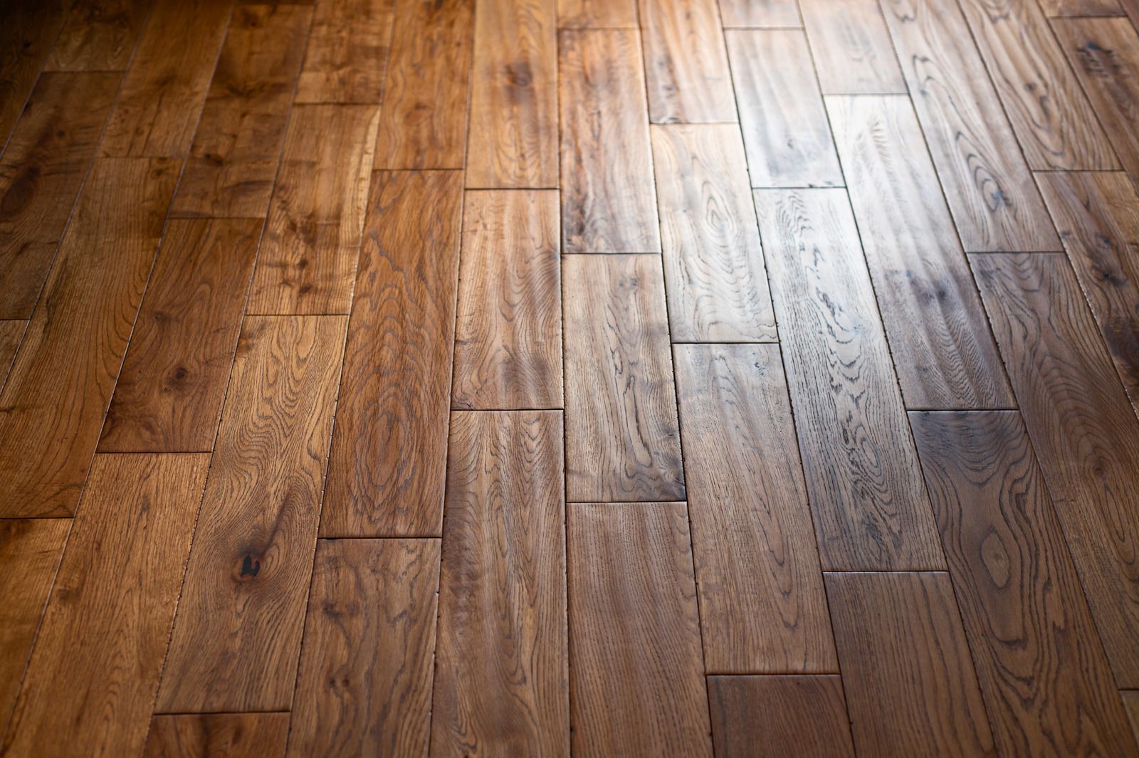 Close-up of warm-toned wooden floorboards with sunlight reflecting across the surface.