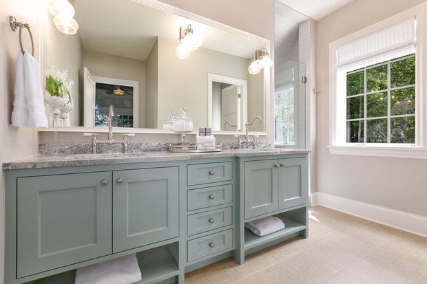 Mint-green bathroom vanity with double sinks, large mirrors, and a window.