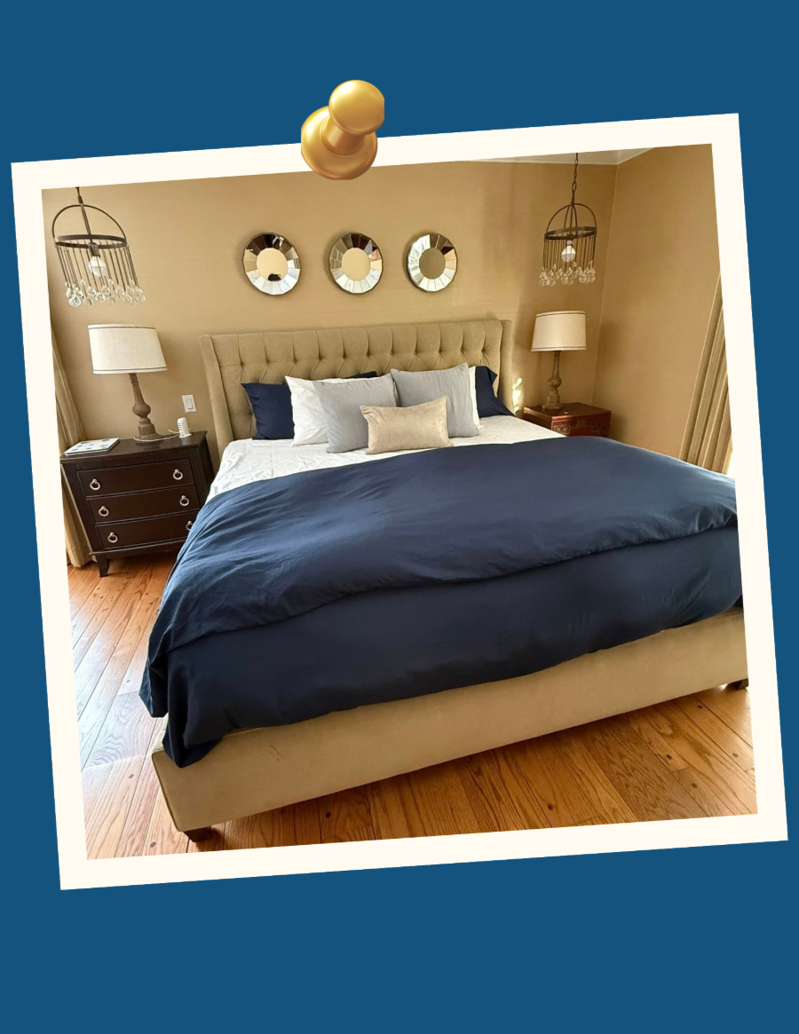 Cozy bedroom with a large navy bedspread, beige walls, nightstands, lamps, and three round wall mirrors