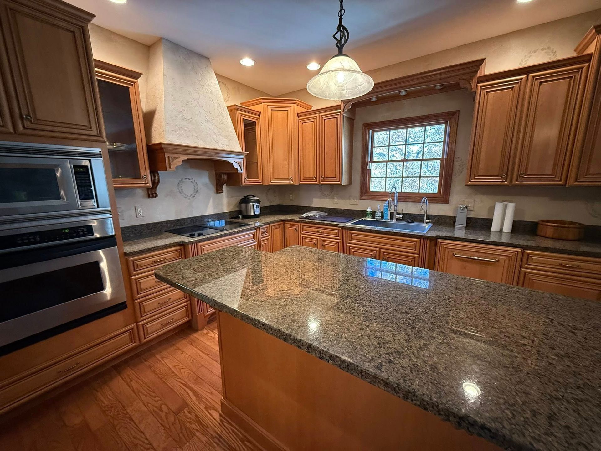 Spacious kitchen with granite island, wooden cabinets, stainless appliances, and a window over the sink.
