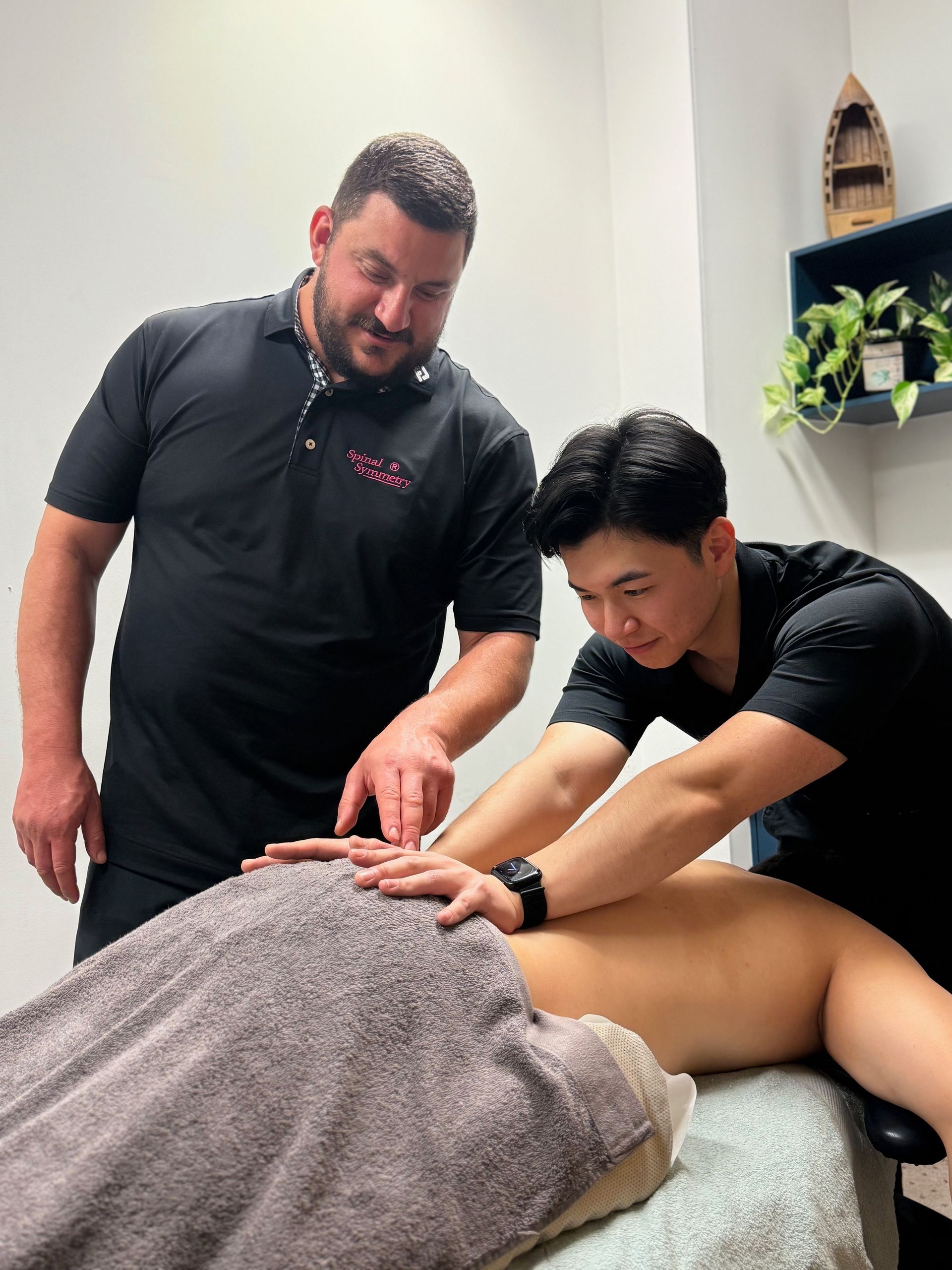 A Man Is Getting A Massage From A Chiropractic practitioner — Spinal Symmetry In Salamander Bay, NSW