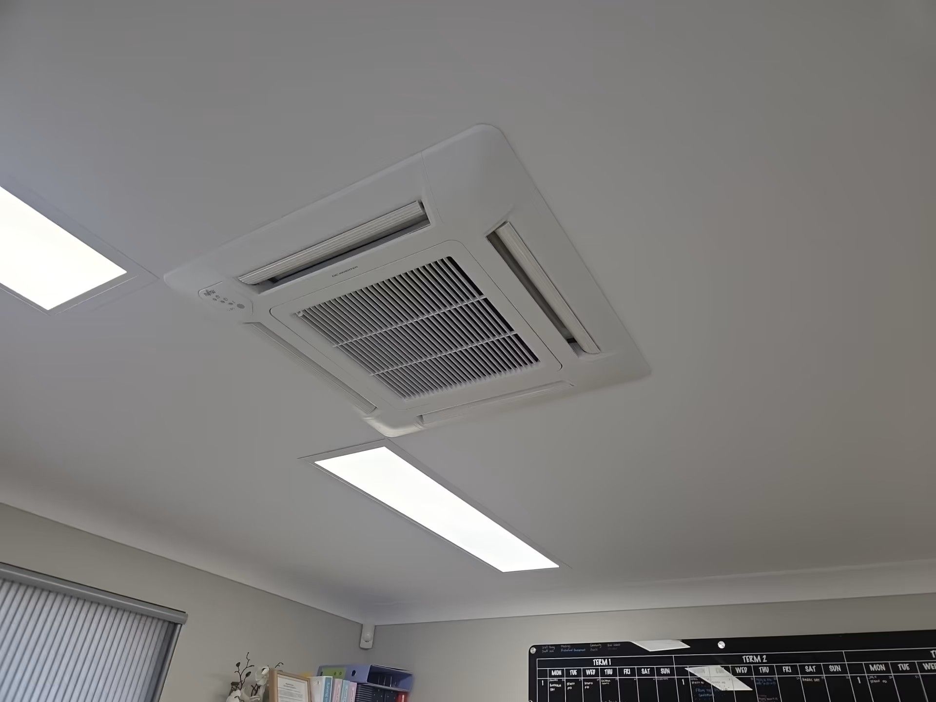 Ceiling with a circular vent, red pipe, and two rows of small spotlights on a white surface Ceiling with a circular vent, red pipe, and two rows of small spotlights on a white surface