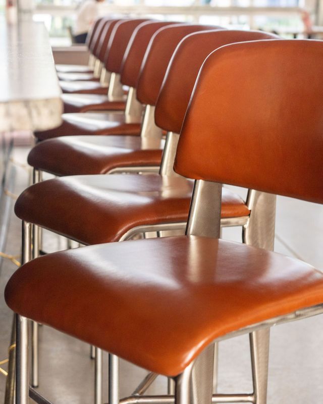 Row of brown vinyl bar stools with chrome legs in a bright cafe