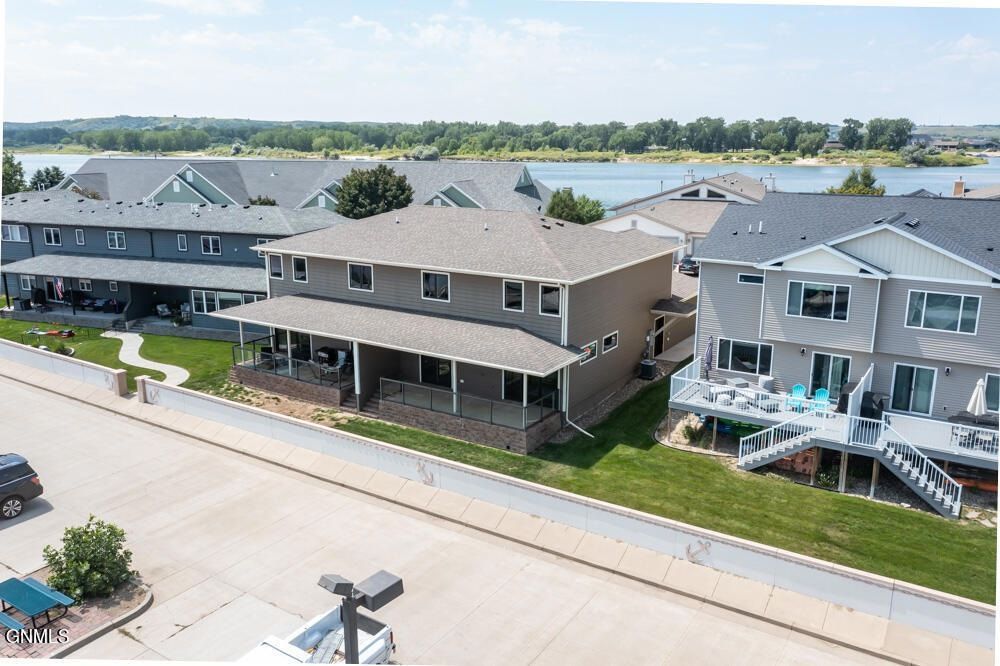 Aerial view of residential townhomes with decks overlooking a body of water on a sunny day.