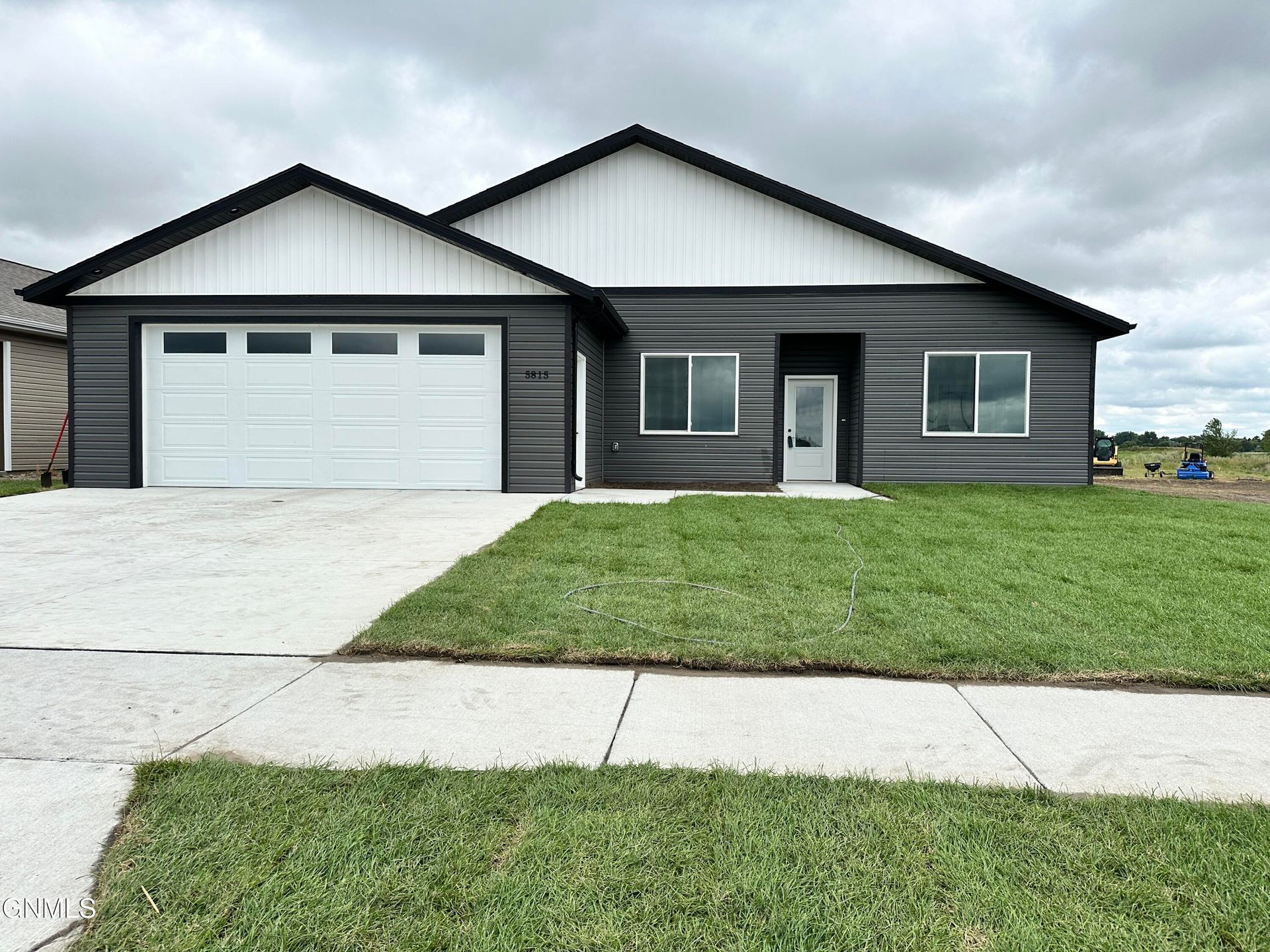 A modern single-story house with dark gray horizontal siding, white vertical gables, and a white two-car garage.