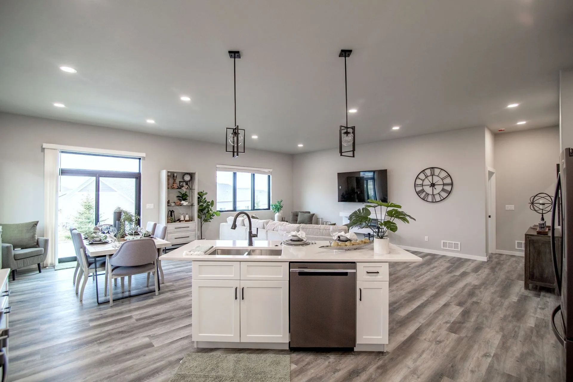 Modern open-concept kitchen with a center island, white cabinets, stainless steel dishwasher, and dining and living areas.