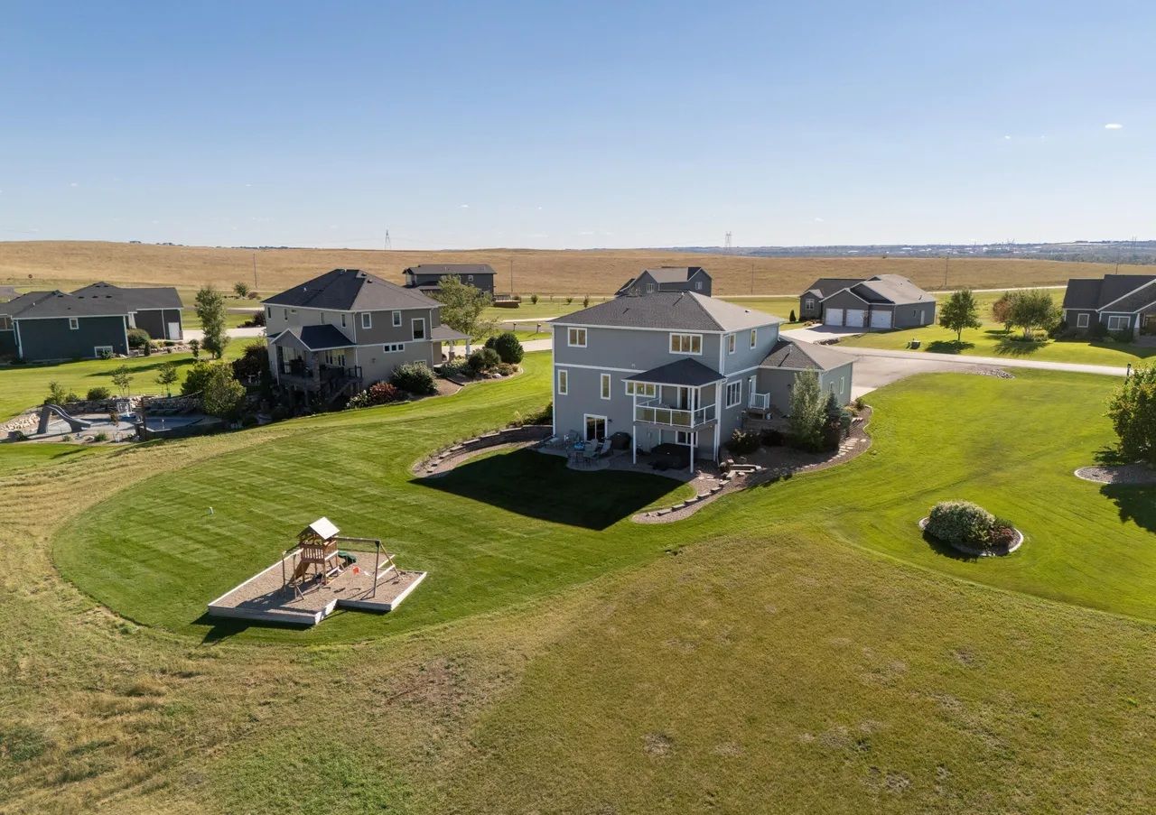 Aerial view of a residential neighborhood with several large homes, green lawns, and a backyard playground.