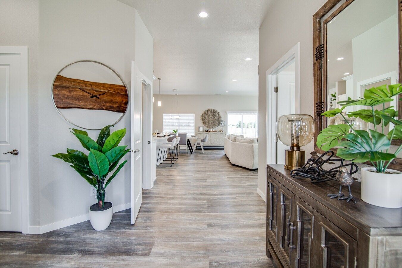 An entryway with wood-look flooring leads to a bright living area, featuring a decorative wall art piece and a console.