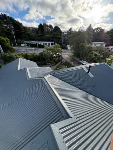 A close up of a roof of a house with trees in the background.