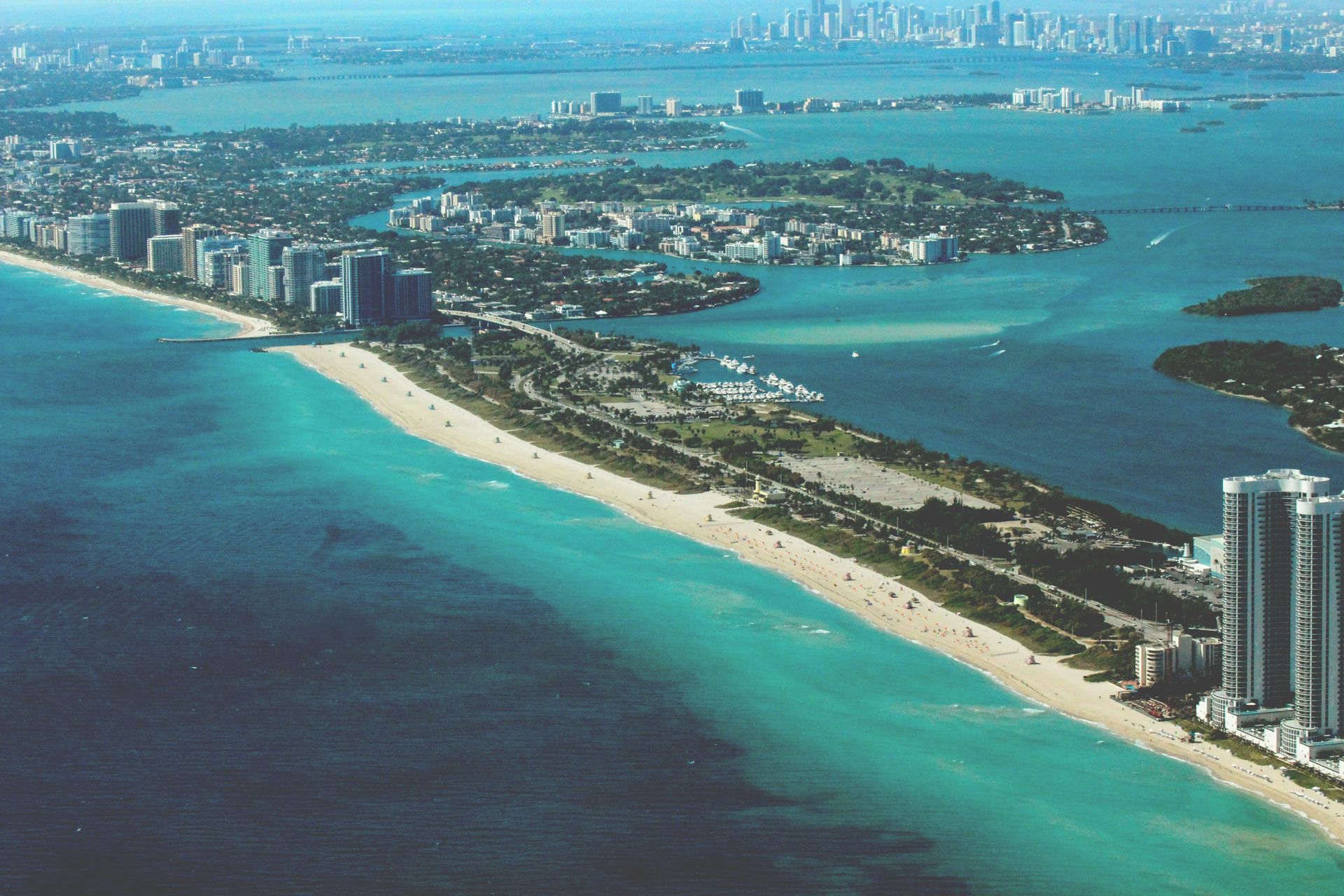 Aerial view of Miami Beach, with turquoise water, sandy beach, and city skyline.